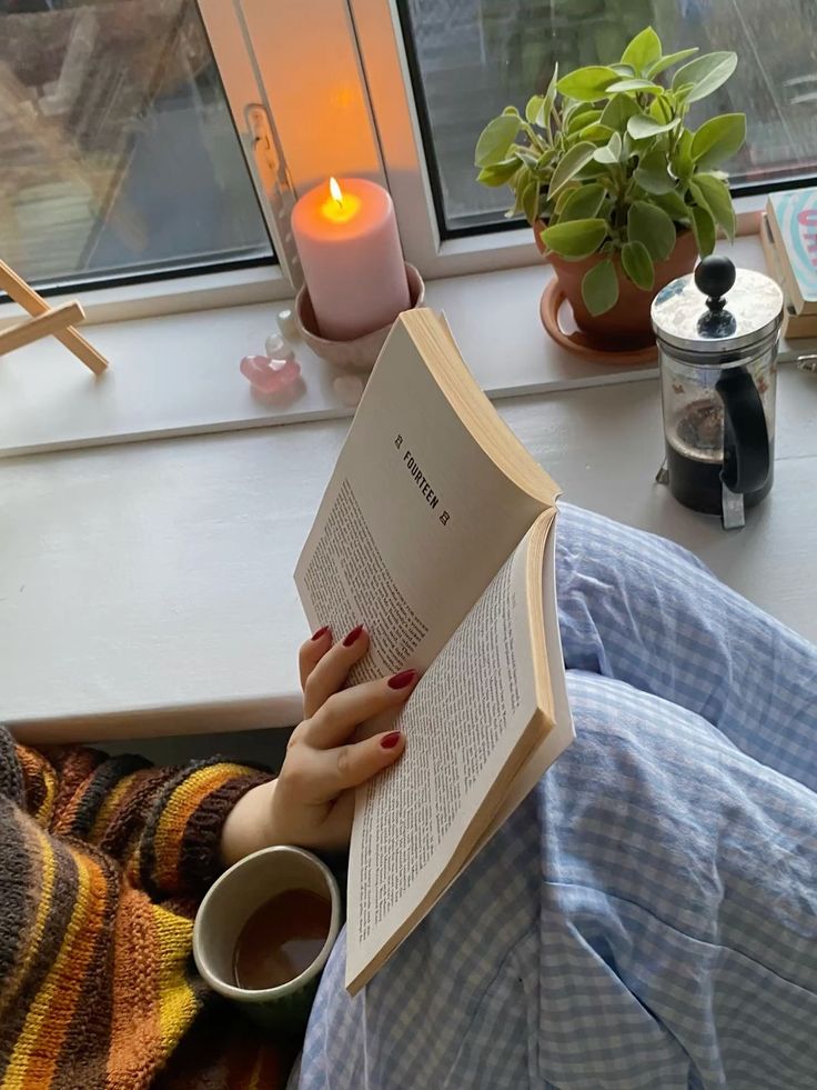 "Cozy rainy day aesthetic, with warm striped sweater, gingham pajamas, and a book on the windowsill"