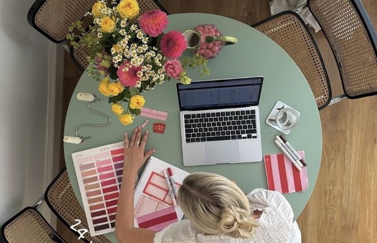 "Productive rainy day setup, woman planning new project with a laptop, notebook, and markers"