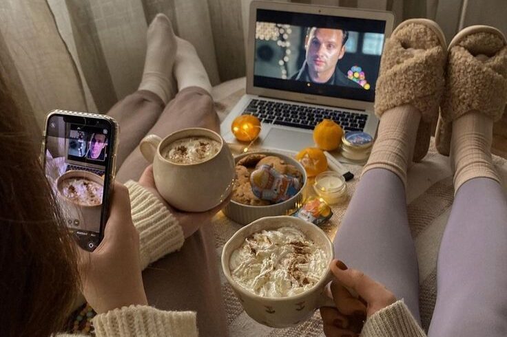 "Rainy day aesthetic bedroom setup watching movies with warm cocoa and fairy lights"